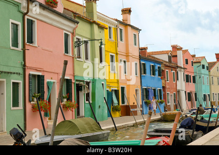 Linea di imbarcazioni canal nell isola di Burano vicino a venezia conosciuta per la produzione di merletti elegantemente vestito giovane donna cammina da case colorate Foto Stock