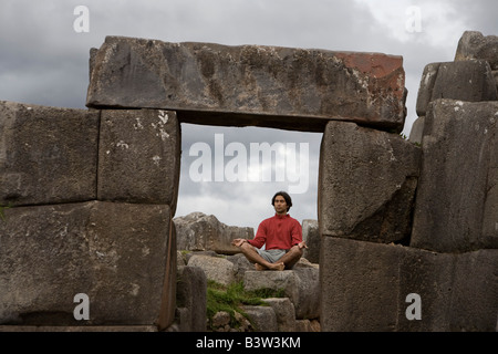 Un giovane uomo medita in antiche rovine Inca al di fuori di Cuzco, Perù Foto Stock