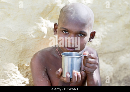 Ragazzo indiano con tazza di metallo, acqua potabile. India Foto Stock