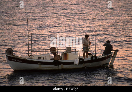 Piccola barca da pesca ritorna al porto al tramonto su Creta, Grecia. Foto Stock