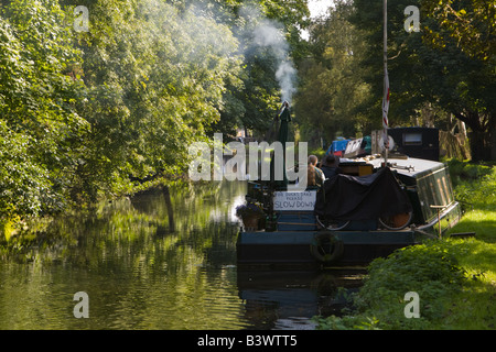 Il fumo dal camino ormeggiate imbarcazioni strette sul Grand Union Canal Foto Stock