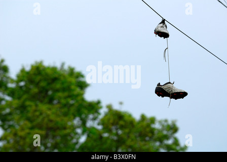 Un paio di scarpe da calcio appeso su power-linee Foto Stock