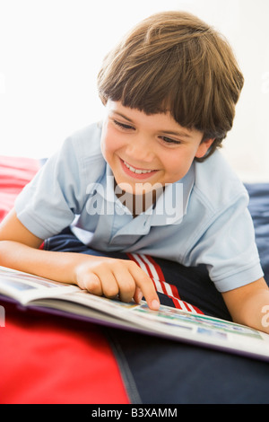 Giovane ragazzo disteso sul suo letto la lettura di un libro Foto Stock