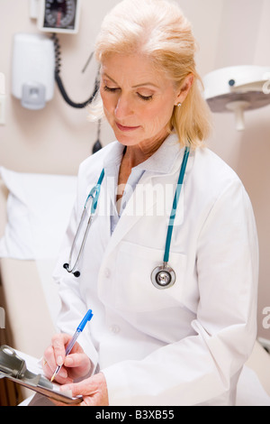 Di mezza età medico femmina la scrittura su una clipboard Foto Stock