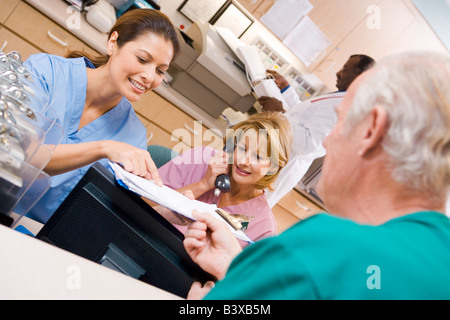 Gli infermieri a discutere di una clipboard presso l'area ricevimento in un ospedale Foto Stock