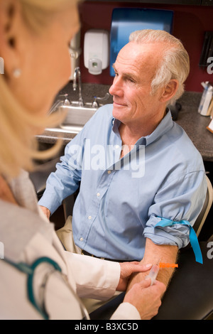 Uomo di mezza età avendo sangue test svolto Foto Stock