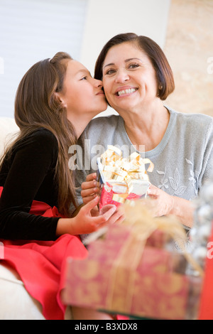 Nipote di baciare la nonna sulla guancia e dando il suo regalo di Natale Foto Stock