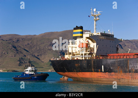 Un rimorchiatore assiste alla poppa di una nave da carico come si arriva nel porto. Foto Stock