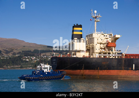 Un rimorchiatore assiste alla poppa di una nave da carico come si arriva nel porto. Foto Stock