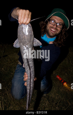 Pescatore con un grande pesce gatto barbell catturato di notte quando si nutrono. Kafue Zambia Africa Foto Stock