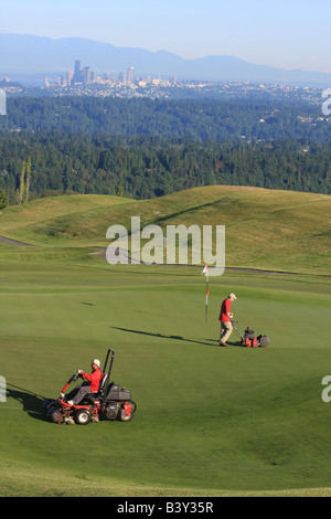 Nelle prime ore del mattino, con la skyline di Seattle in background, i Verdi equipaggio preparare il Newcastle Golf Club per giocare. Foto Stock