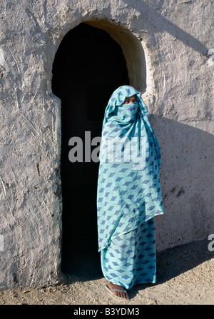 Sudan, Fiume Nilo, Quarta Cataratta. Una donna Nubiano, il suo viso coperto dal suo velo per denotare la sua fede musulmana, sorge al di fuori della veranda della sua casa. Lo stile di una veranda arch è tipico del popolo Nubiano. Il villaggio dove vive sul Fiume Nilo, vicino a Shaallal arraabia o la quarta cataratta, sarà allagato nel 2008 quando un enorme finanziato araba, cinese-costruzione della diga idroelettrica verrà completata. Già alcuni villaggi sono stati spostati in terre irrigate lontano. Foto Stock