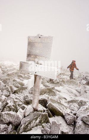 L'uomo escursioni invernali. Rime ghiaccio ricopre le rocce e un segnavia sul monte Washington in le White Mountains del New Hampshire Foto Stock