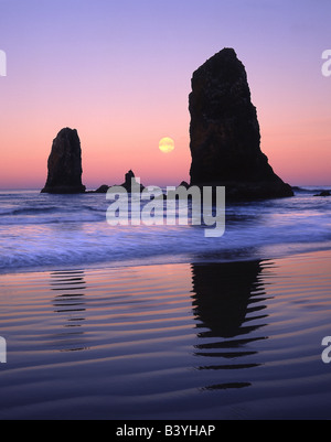 Stati Uniti d'America, Oregon, Cannon Beach.Gli aghi monoliti di roccia di sunrise mostra luna al calare della luna. Foto Stock