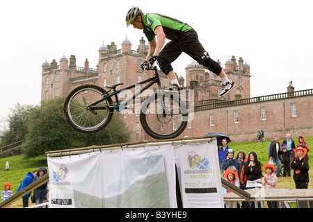 Il 7Stanes Mountain Bike Team di visualizzazione al castello di Drumlanrig biker in piedi sulla ruota alta sopra la folla tour della Gran Bretagna Scozia UK Foto Stock