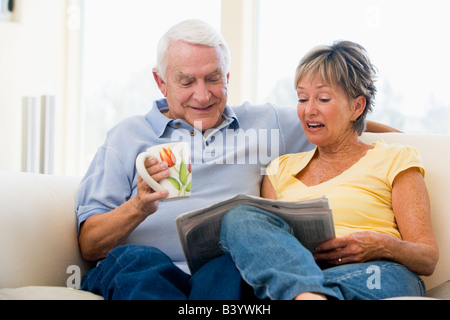 Matura in soggiorno leggendo il giornale con caffè sorridente Foto Stock