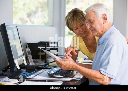 Matura in home office con computer e documenti Foto Stock