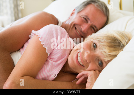 Coppia giacendo in letto sorridente Foto Stock