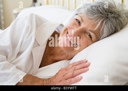 Donna giaceva a letto sorridente Foto Stock