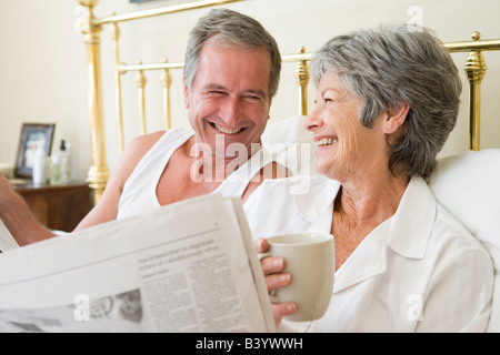 Matura in camera con caffè e quotidiani sorridente Foto Stock