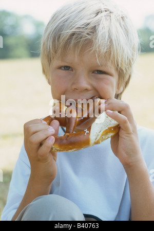 Ragazzo (6-7 anni) mangiando pretzel Foto Stock