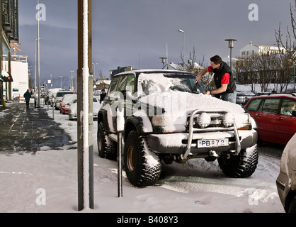 L'uomo la rimozione di neve dalla sua vettura, Reykjavik, Islanda Foto Stock