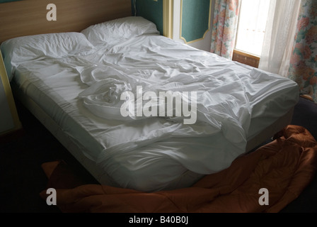 Camera d'albergo con letto doppio, letto non fatto. Fogli ondulati HOMER SYKES Foto Stock