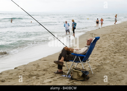 Pesca in mare anziani spiaggia anziani anziani anziani anziani anziani attivo anziani oap Canet Plage nr Perpignan sud della Francia. Un uomo anziano che pesca seduto su una sedia a sdraio Foto Stock