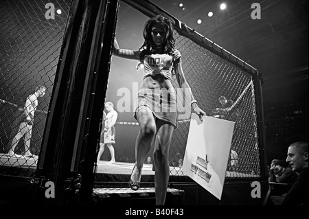 Anello femmina ragazza esce dalla gabbia dopo aver premuto fino alla scheda per indicare il round 2 della lotta Foto Stock