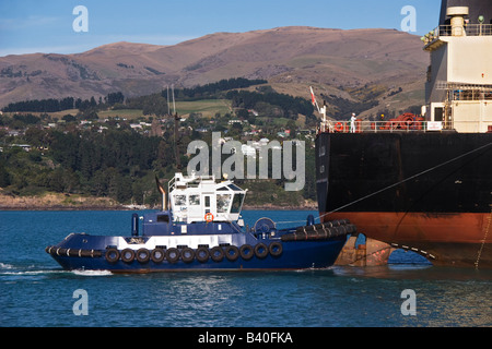 Un rimorchiatore assiste alla poppa di una nave da carico come si arriva nel porto. Foto Stock