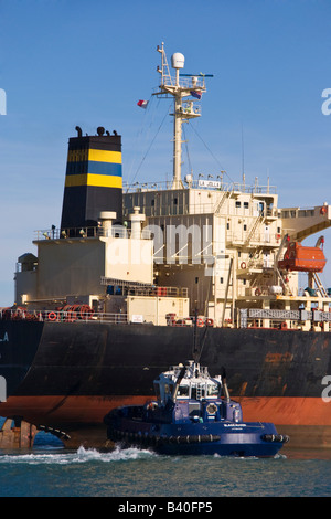 Un rimorchiatore assiste alla poppa di una nave da carico come si arriva nel porto. Foto Stock