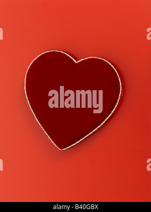 A forma di cuore il giorno di san valentino scatola di cioccolato su sfondo rosso Foto Stock