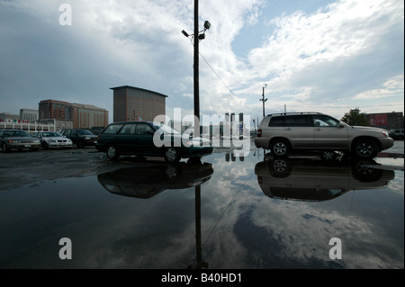 Un cloudscape si riflette in una grande pioggia pozza d'acqua in un parcheggio nei pressi del Boston ICA Foto Stock