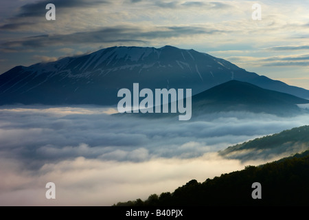 La nebbia giacente sul piano Grande all'alba con le montagne del Parco Nazionale dei Monti Sibillini che si eleva al di sopra, Umbria, Italia Foto Stock