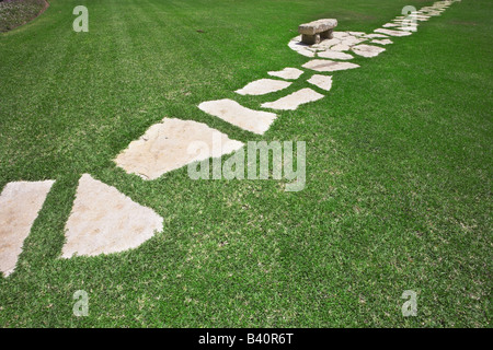 Percorso e banco di pietra nel mezzo di un prato prato verde Foto Stock