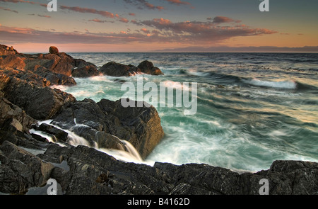 Stati Uniti d'America, Washington, le Isole San Juan. Onde infrangersi sulla riva meridionale di Lopez Island al tramonto. Foto Stock