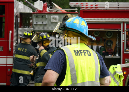 Un gruppo di vigili del fuoco in una scena di emergenza di una casa di fuoco Foto Stock