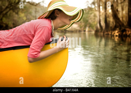 Una giovane ragazza si rilassa sulla sua canoa in acqua limpida, cipressi fiume di acqua dolce primavera in alta Springs, in Florida. Foto Stock