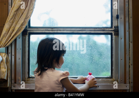 4 anno vecchia ragazza riprodotto nella finestra di un treno in movimento. Foto Stock