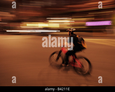 Corriere di bicicletta pedalando attraverso la notte a Londra Regno Unito Foto Stock