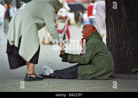 Pedone dare soldi a una donna di accattonaggio, Riga, Lettonia Foto Stock