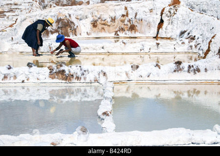 Due donne indiane il lavoro estraendo il sale nel sale di pool di Salineras de Mara vicino a Cuzco, Perù. Foto Stock