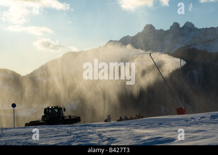 Un pennacchio di neve artificiale da impianti di innevamento programmato nelle Alpi Francesi, contro le montagne e le nuvole in background. Foto Stock
