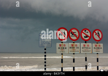 Spiaggia cartelli di avvertimento scritto in inglese e in cinese di Taiwan come approcci di tempesta. Foto Stock