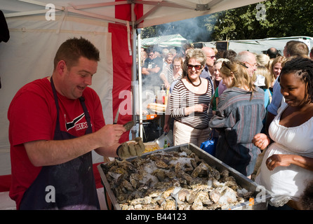 Man shucking ostriche per i clienti in attesa a un open air di stallo alimentare, Brighton, Inghilterra Foto Stock