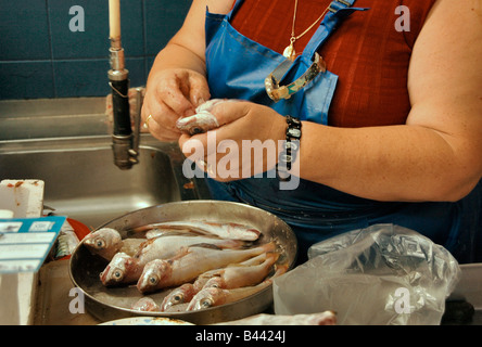 Una donna filetti e prepara il pesce per la vendita a un mercato coperto in Portogallo. Foto Stock