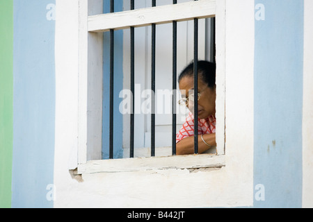 Un cubano di persona guarda la strada di Trinidad attraverso le barre. Foto Stock