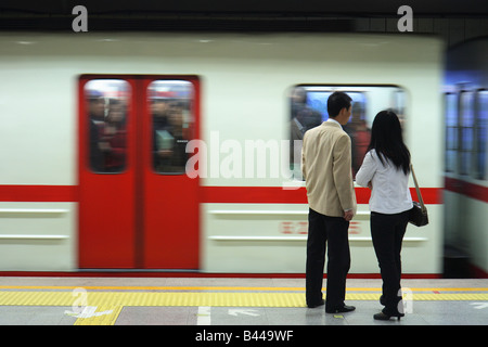 Coppia in attesa in corrispondenza di una stazione della metropolitana a Pechino in Cina Foto Stock