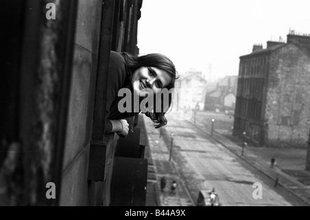 Un giovane lavoratore pop la sua testa fuori da una delle finestre in un alloggiamento di baraccopoli in Gorbals distretto di Glasgow Gennaio 1966 Foto Stock