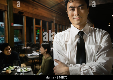 Cameriere asiatico con le braccia incrociate Foto Stock